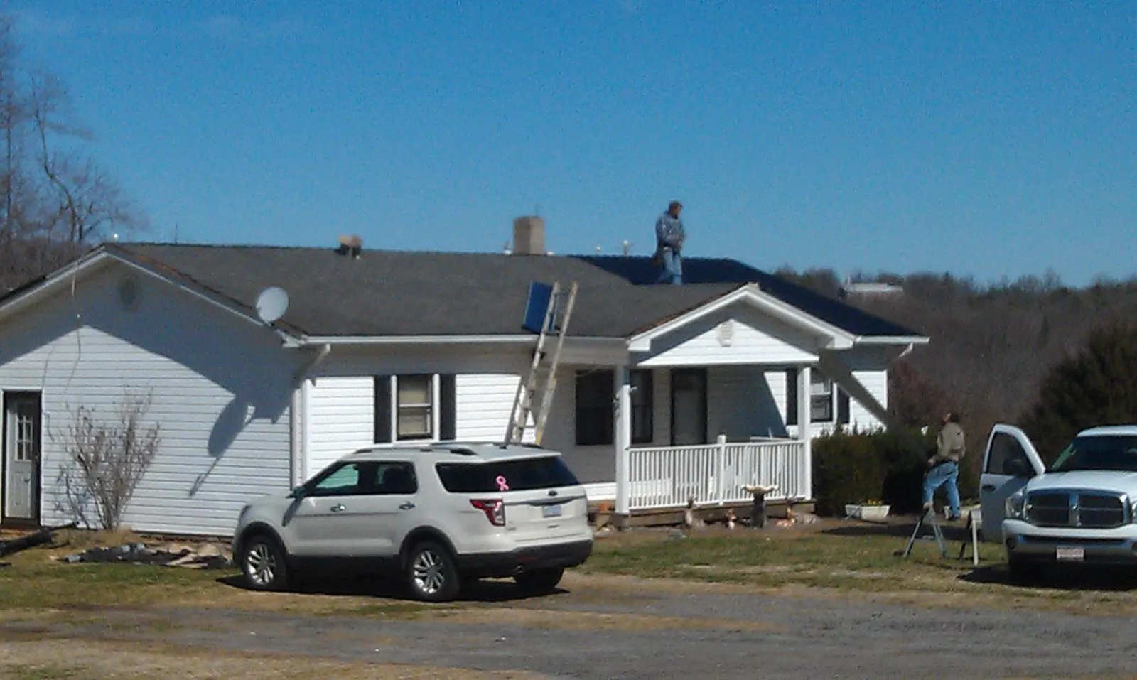 Roofers stripping shingles from a white ranch house roof in Bellwood
